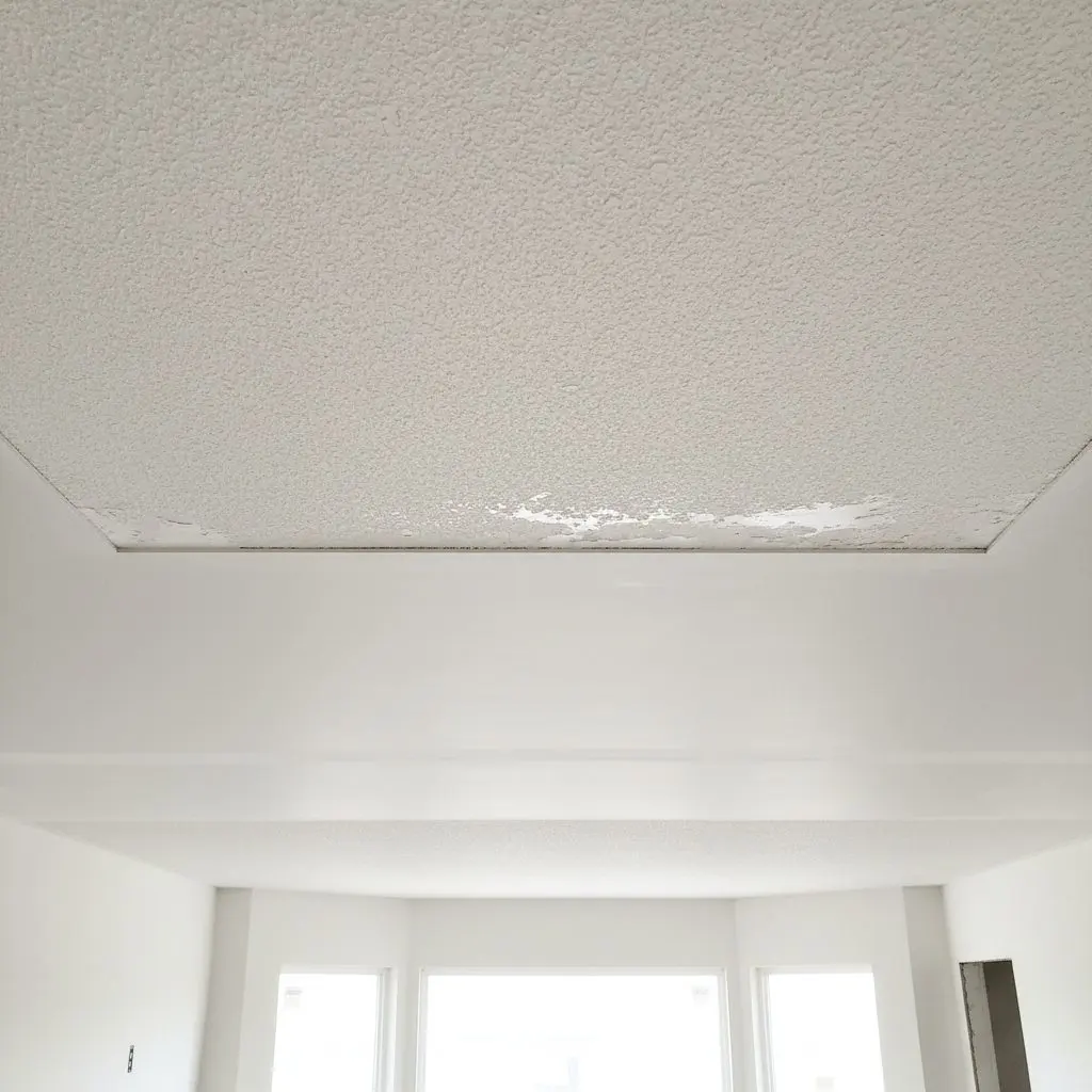 A close, square view looking up at a ceiling where old popcorn texture has been scraped away